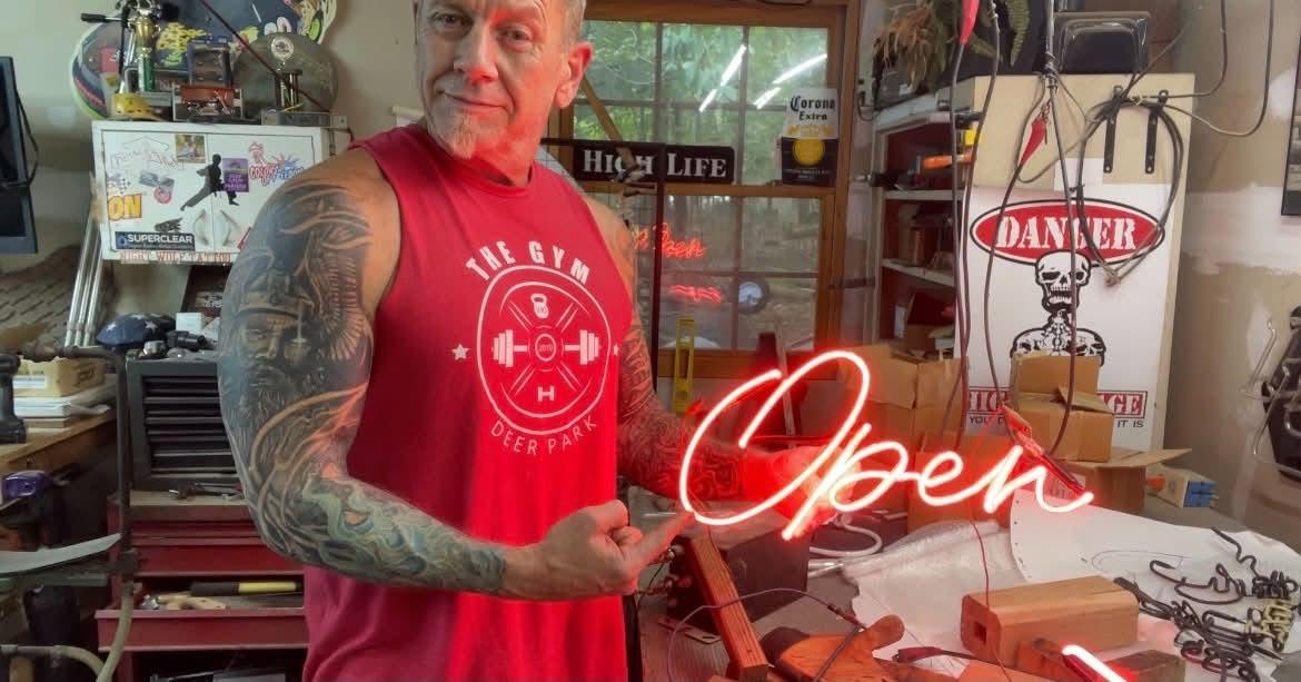Red cursive Open neon being held in the shop